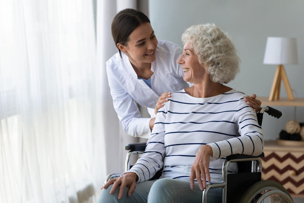 Assisted living staff members helps older woman