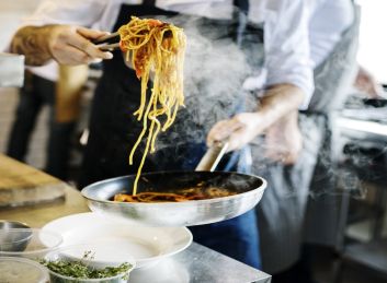 Expert chef preparing gourmet spaghetti in the community kitchen of our retirement home.