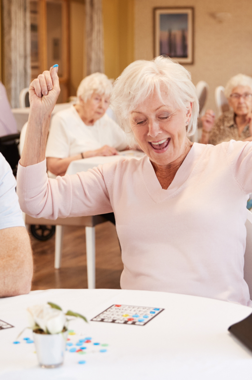 Joyful senior woman celebrates a bingo win at an active retirement community.