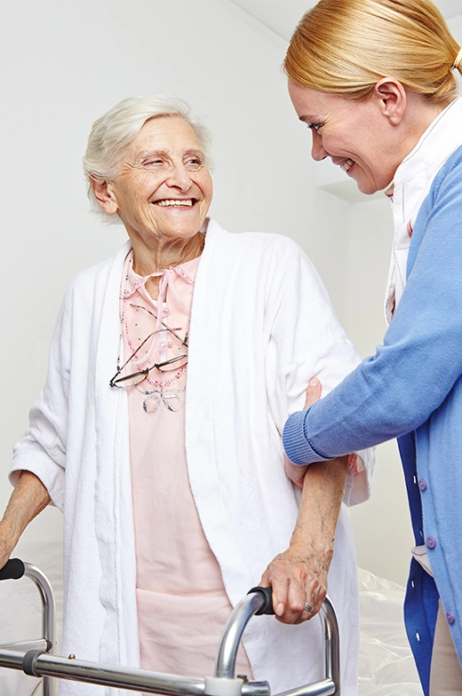 A senior woman in assisted living enjoys a delightful encounter with a cheerful caregiver, exemplifying the compassionate care in our retirement home community.