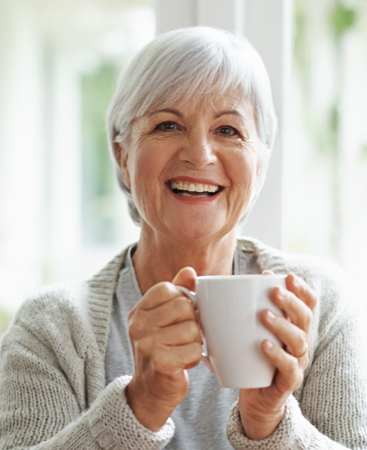 Joyful senior lady sipping tea with a radiant smile at Mira Vie at Green Knoll- Your ideal retirement home.