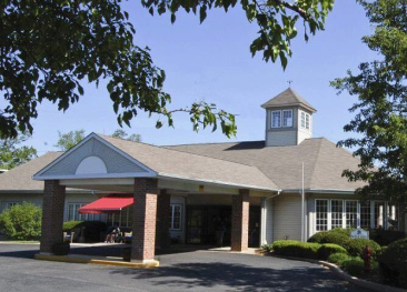 Welcome to our single-level retirement community, featuring a beautiful Mira Vie cupola and a welcoming red awning at the entrance.