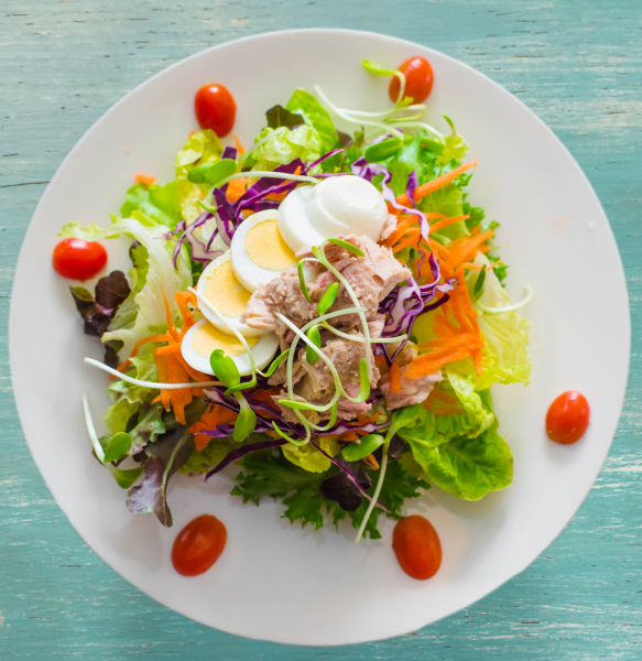 Savor a vibrant mixed salad featuring tuna, eggs, and cherry tomatoes in our retirement community dining room.