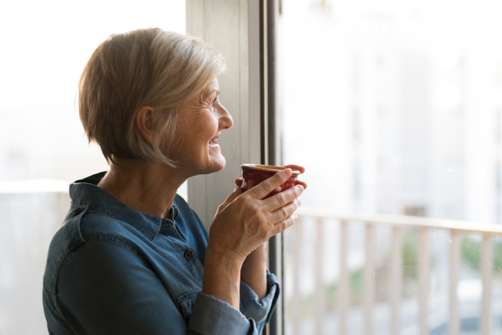 Senior resident enjoys retirement home living while sipping coffee and appreciating the view.