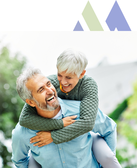 Joyful senior couple from Mira Vie at Manalapan retirement community outdoor piggyback ride.