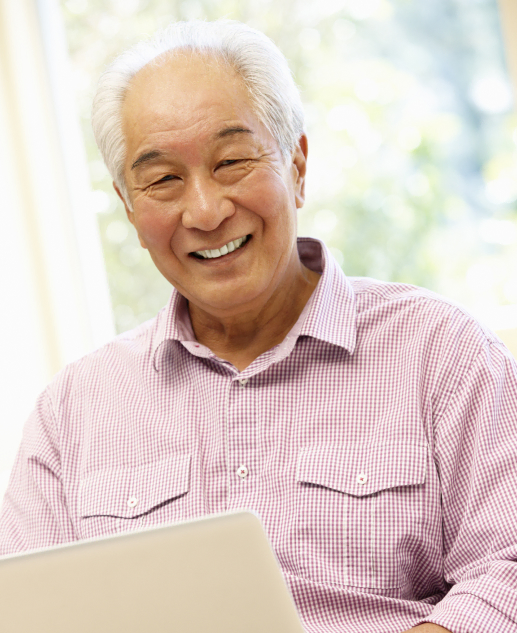 Cheerful senior enjoying laptop use at Mira Vie at Manalapan retirement community.