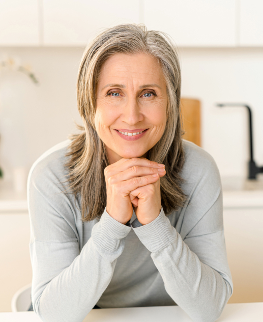 At the Mira Vie at Montville retirement community, a joyful middle-aged woman with silver hair comfortably enjoys her time in the kitchen.