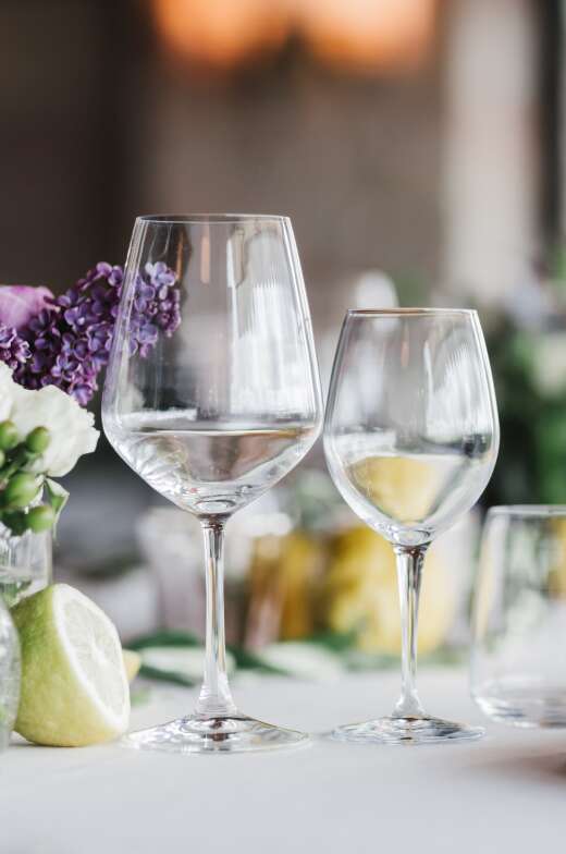 Leisurely retirement living with our community programs, perfectly illustrated by a tranquil setting featuring two empty wine glasses, a floral arrangement, and fruit. The ambiance of a relaxed lifestyle at our senior living home.