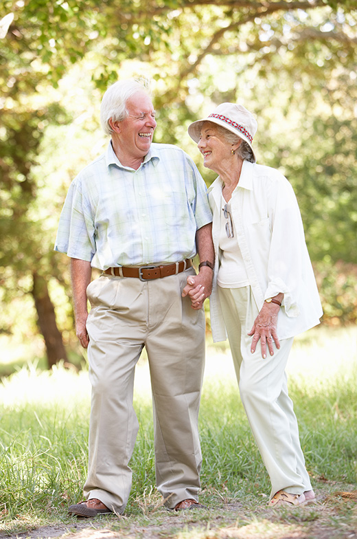 Senior living services as a cheerful elderly couple leisurely strolling, hand-in-hand, in our vibrant retirement community.