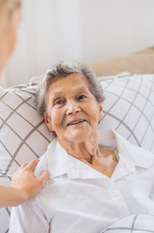 Senior woman happily relaxing on a plush sofa, receiving attentive senior living care in our retirement community.