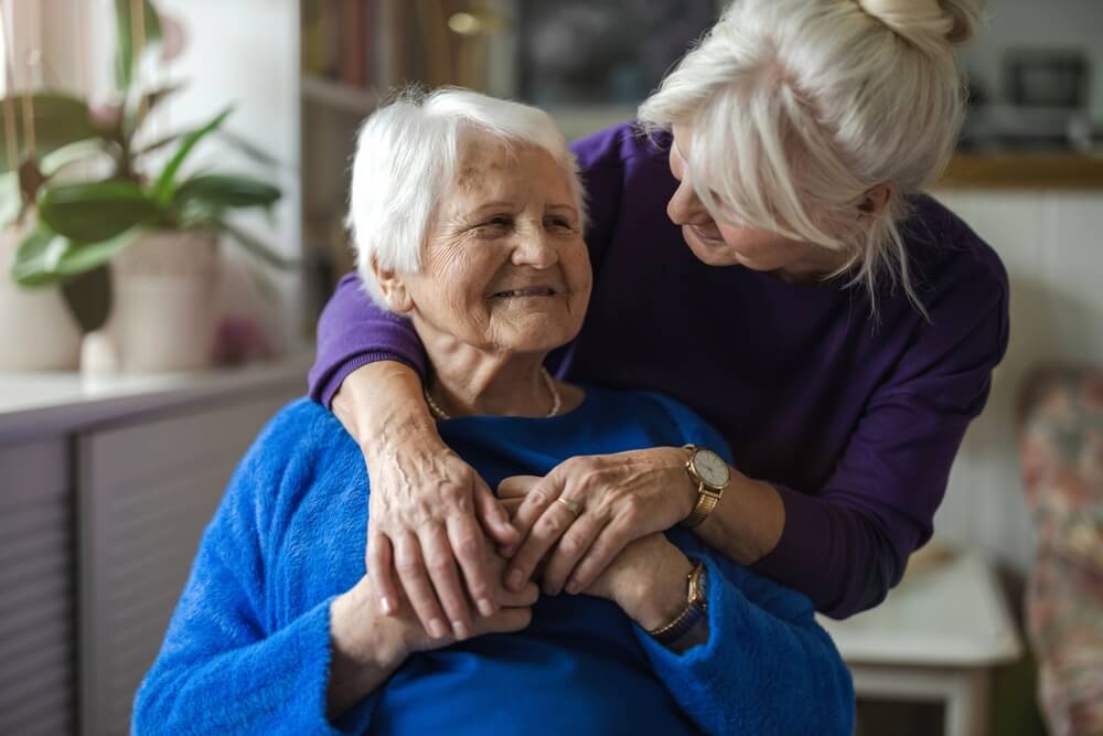 Younger woman embraces older woman - stages of dementia.