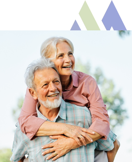 Elderly couple sharing a joyful embrace outdoors at the Mira Vie Retirement Community in Tinton Falls.