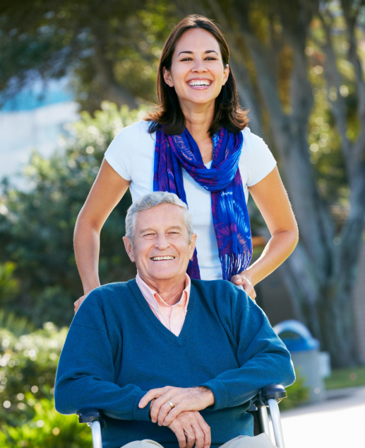 Cheerful senior man enjoys outdoor relaxation in a wheelchair, assisted by a woman at the charming Mira Vie Retirement Community in Toms River.