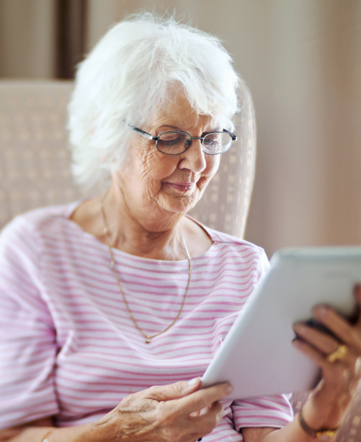 Senior resident at Mira Vie Retirement Community in Toms River enjoys reading on her tablet.