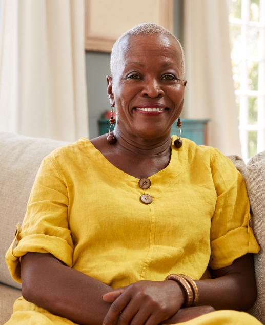 Cheerful lady in a yellow shirt enjoying indoor comforts at Mira Vie at Warren senior living community.