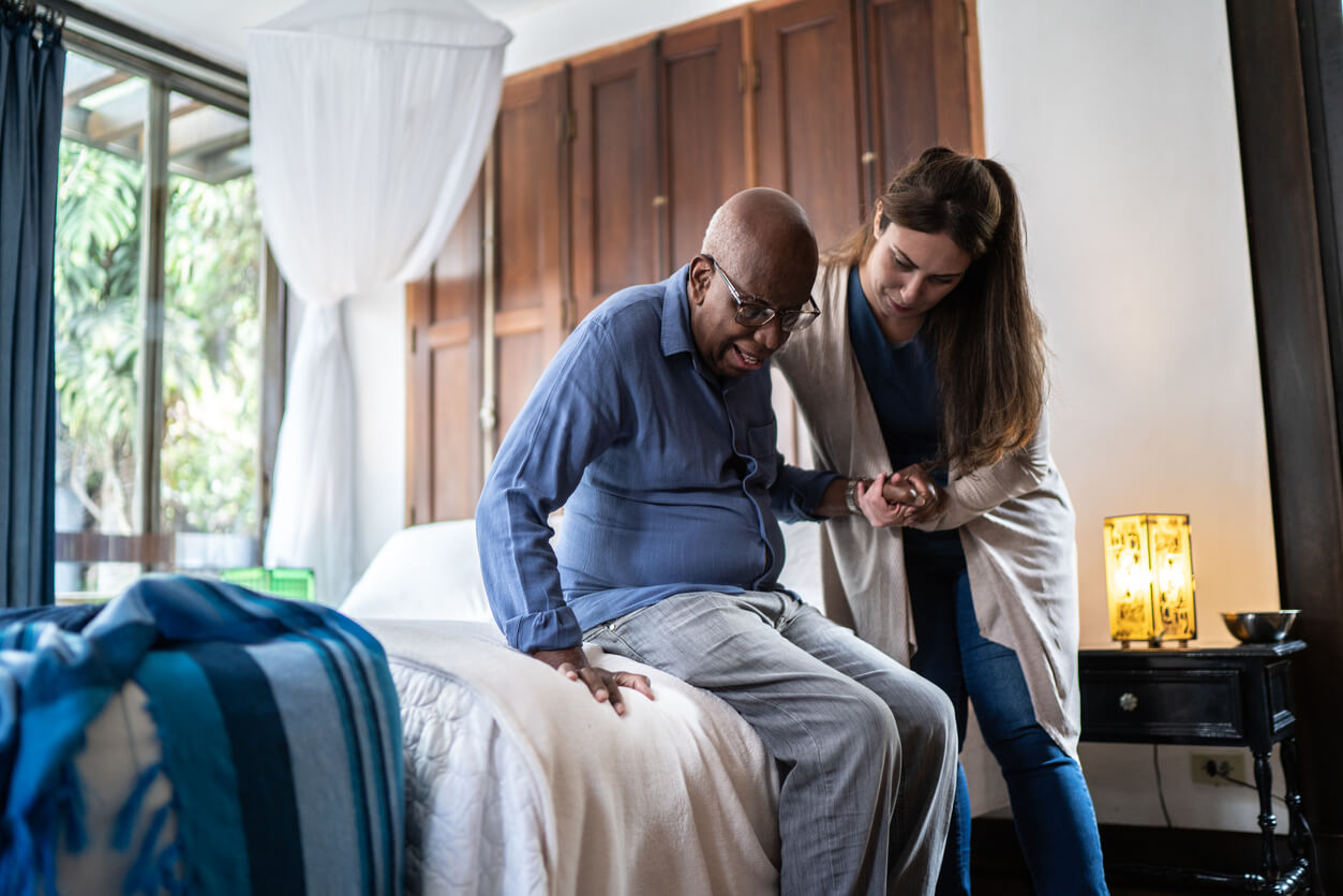 A home health aide helping a senior out of bed