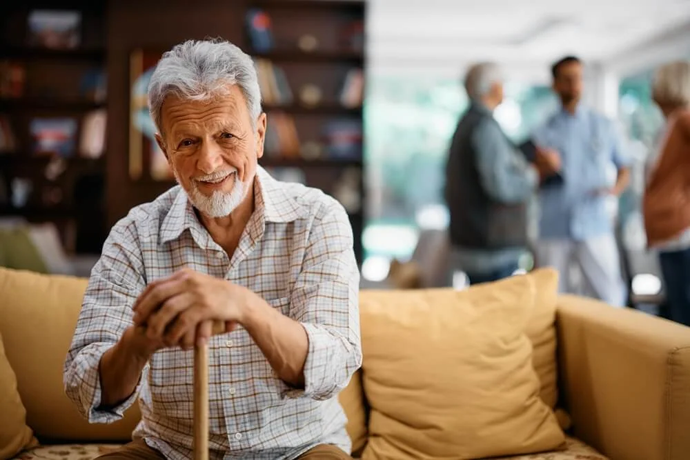 older man sits on couch - assisted living costs