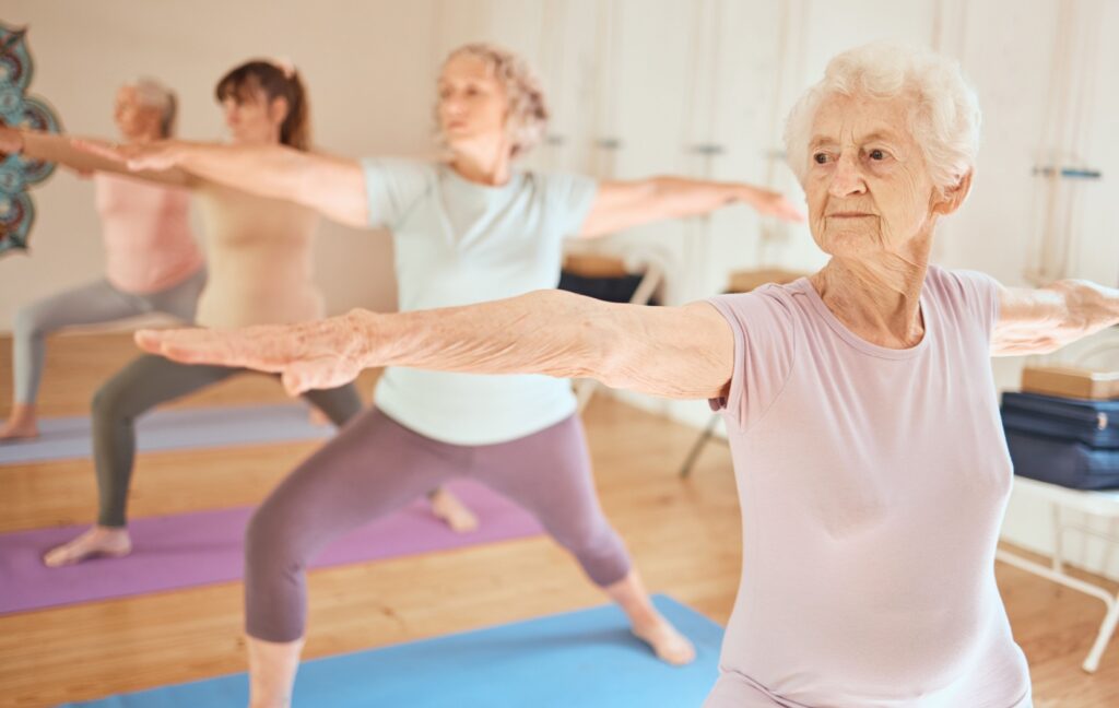 A group of senior women do yoga in a class