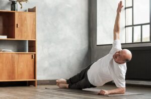 An older adult practicing a side plank exercise on a yoga mat