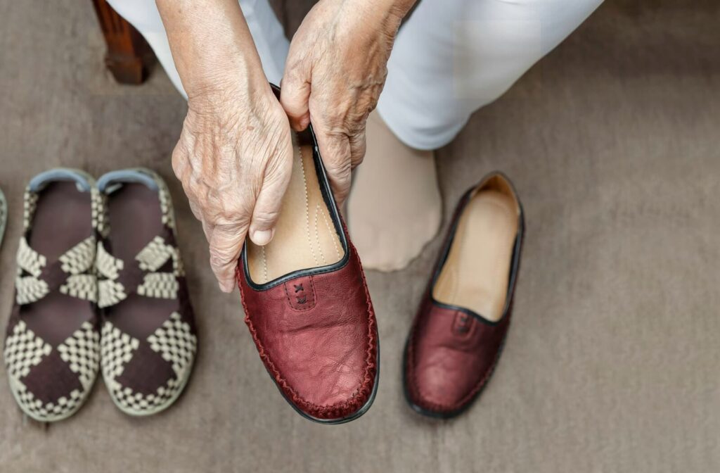 A senior holds one of a pair of red slip-on shoes to try on while out shopping for dementia-friendly footwear