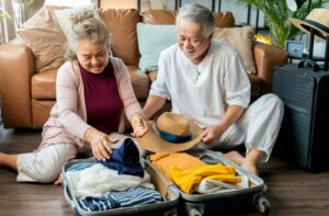 Elderly couple packing a suitcase, preparing to downsize for assisted living.