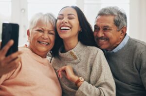 A senior couple takes a selfie with their adult grandchild, who came to visit them at their assisted living home