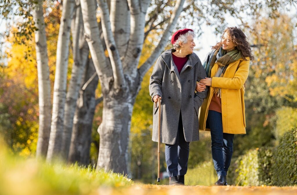 An adult child and their older parent enjoy a nice autumn walk together.