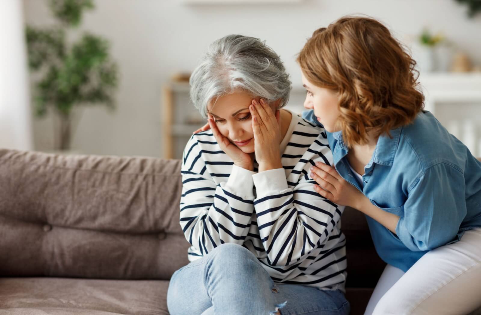 A concerned adult attempts to comfort a senior parent with dementia having a bad day