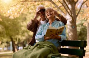 A happy senior couple relax in a local park and enjoy birdwatching together.