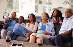 A multi-generational picture of an entire family enjoying a movie night featuring the 2009 film Up.