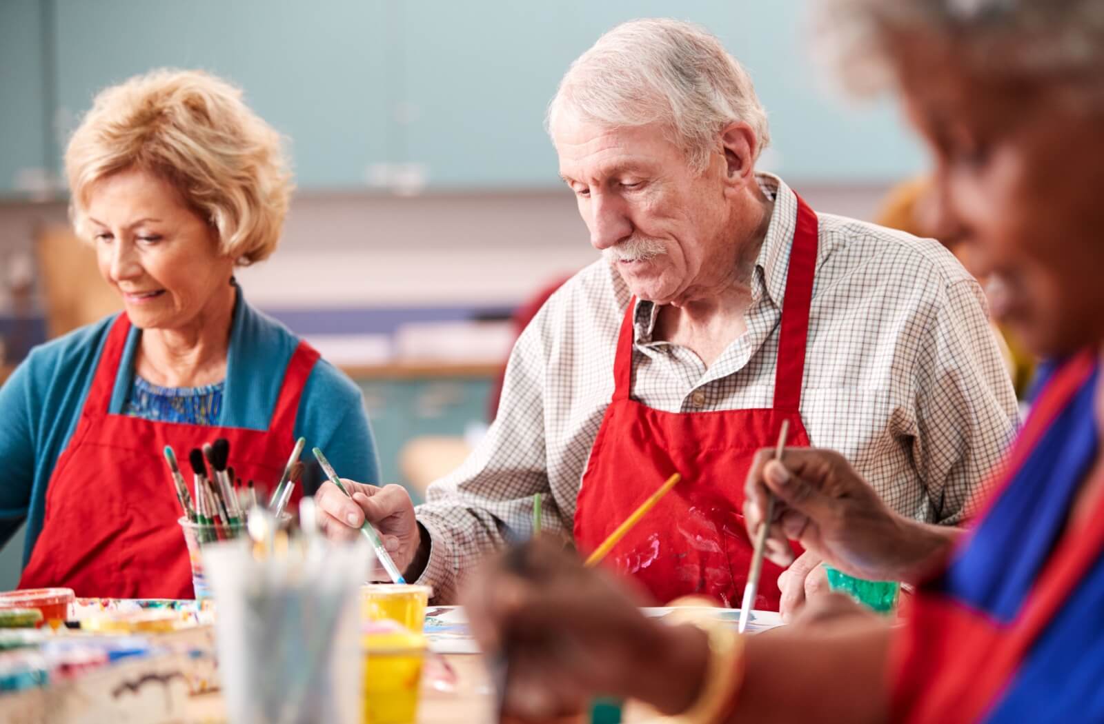 A group of seniors participate in a painting class in their memory care community.