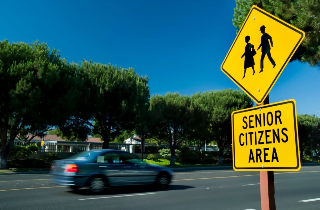 A yellow traffic sign reads, "SENIOR CITIZENS AREA" along a quiet, sunny street.