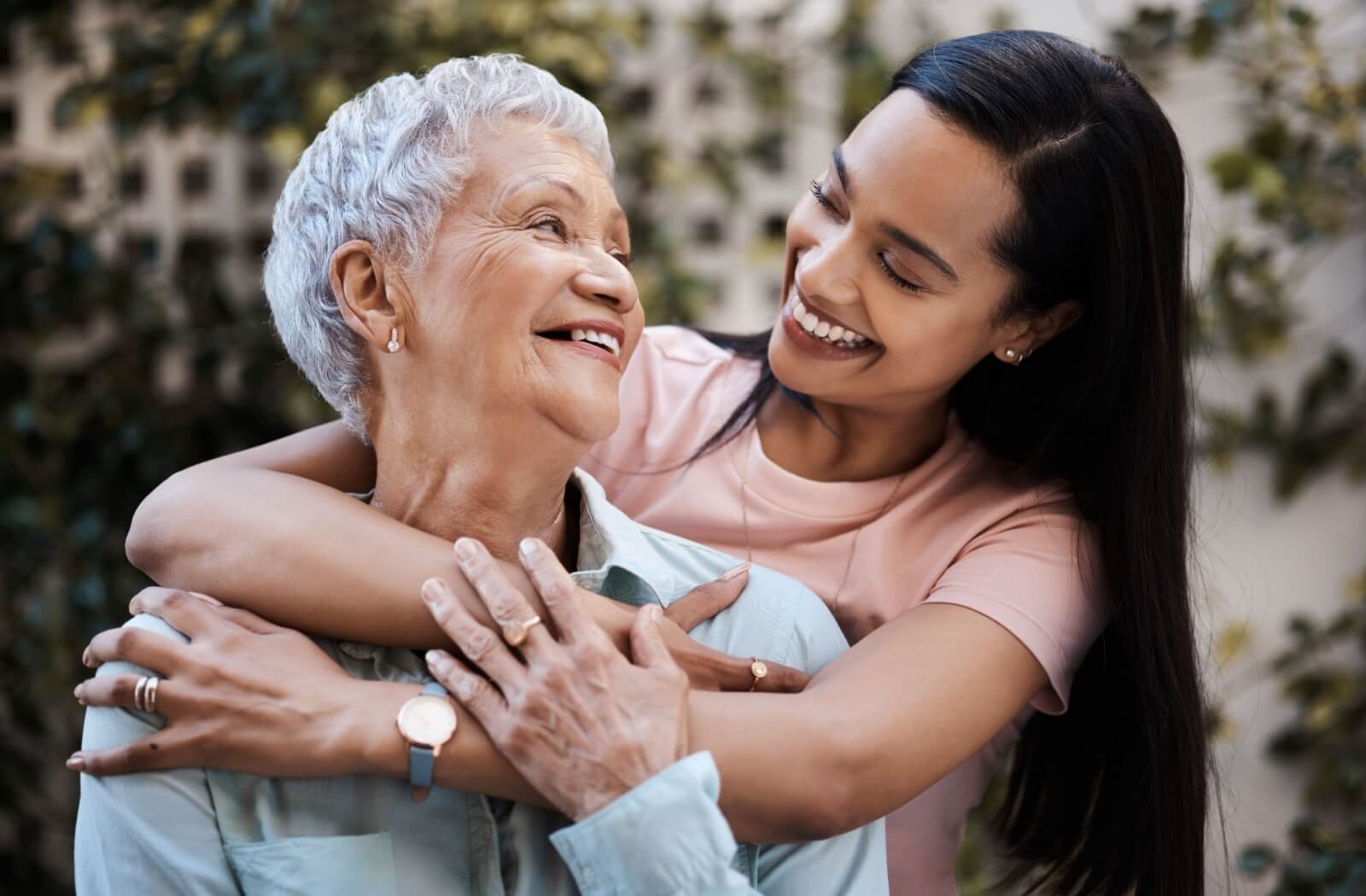 An adult child happily embraces their mature parent.