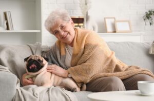 A senior snuggles a happy pug at their community apartment.