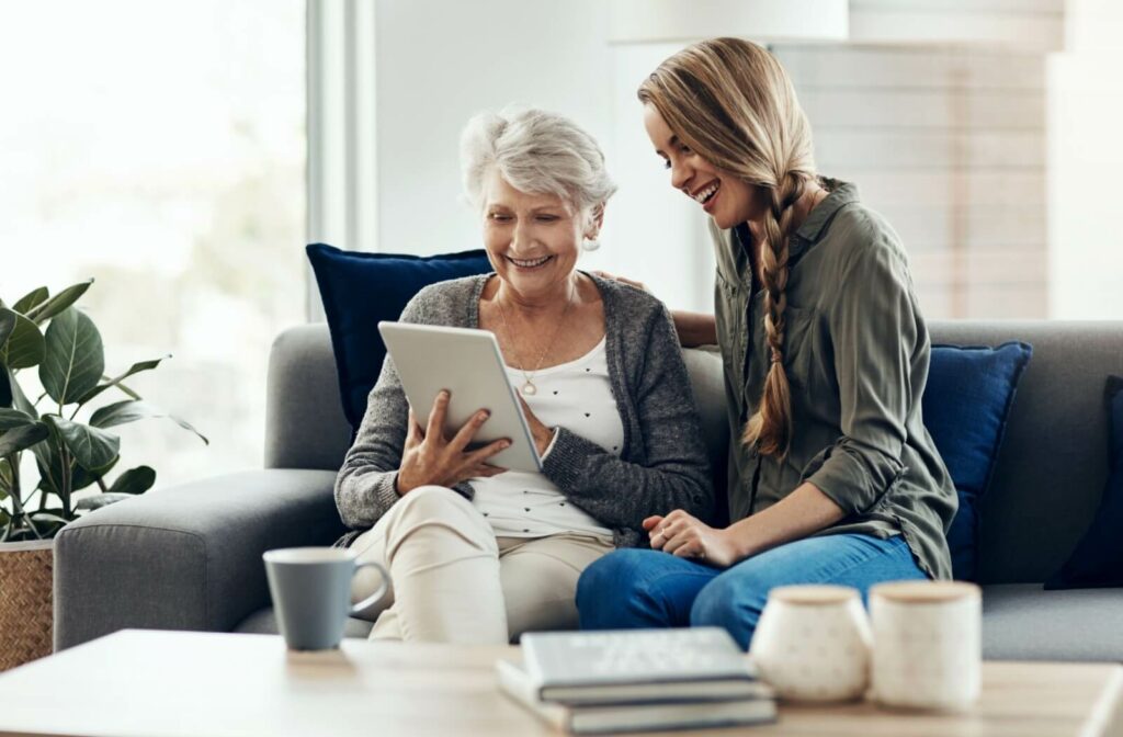 An adult child visiting their parent in assisted living while connecting with digital devices.