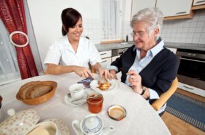 A caregiver helps prepare toast and jam for a senior resident.