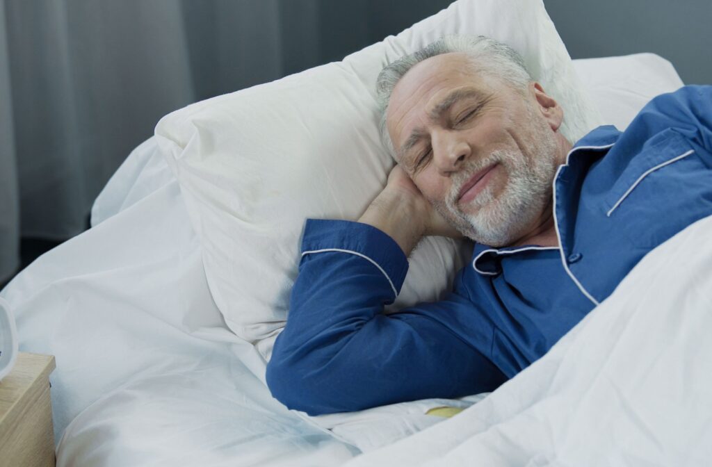 A happy senior sleeps peacefully in their bed at night.