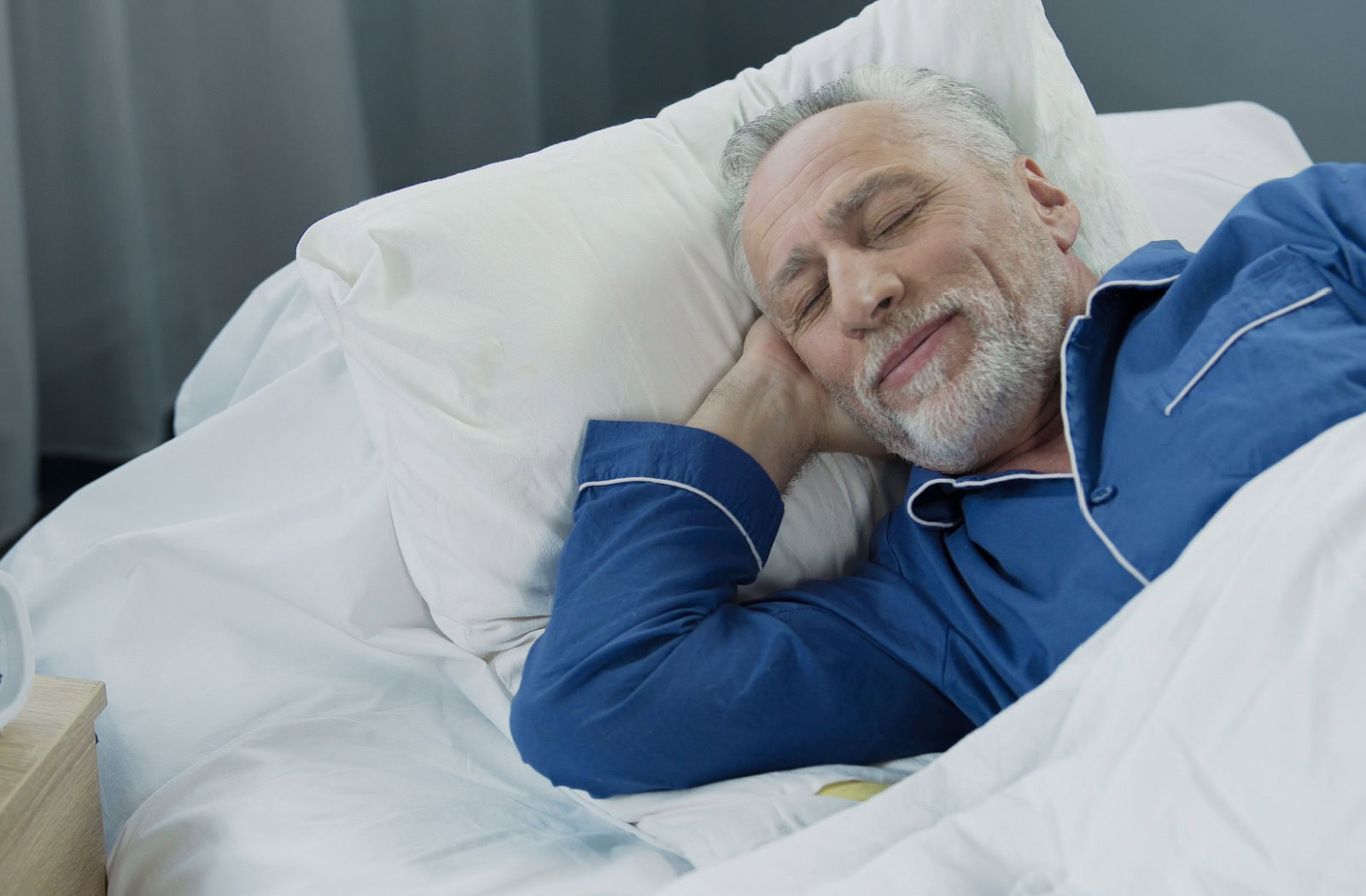 A happy senior sleeps peacefully in their bed at night.