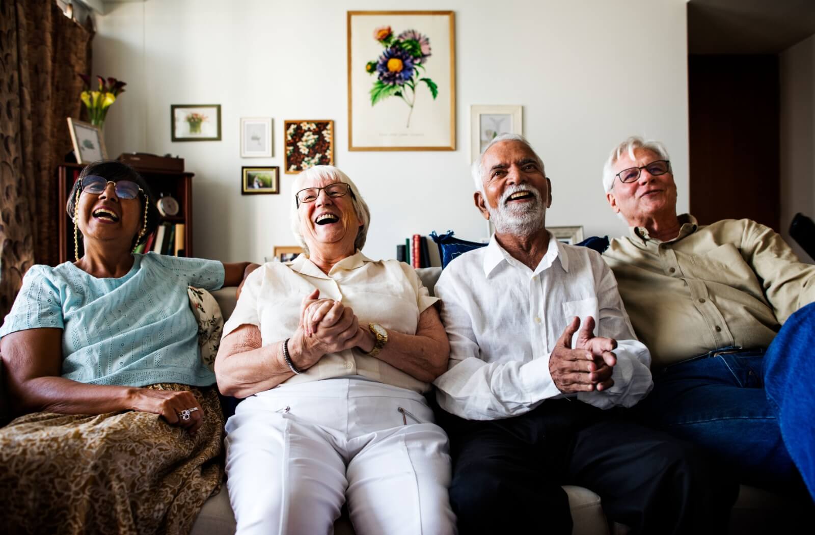 A group of seniors happily watching TV together in the common room of a senior living community, enjoying each other’s company.
