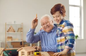 A cheerful older adult works on a carpentry project with their grandchild.