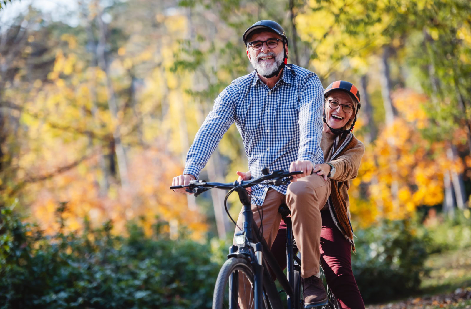 A pair of happy seniors go on a bike ride through the park together.