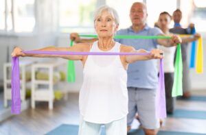 A group of seniors in a class exercises using resistance bands.