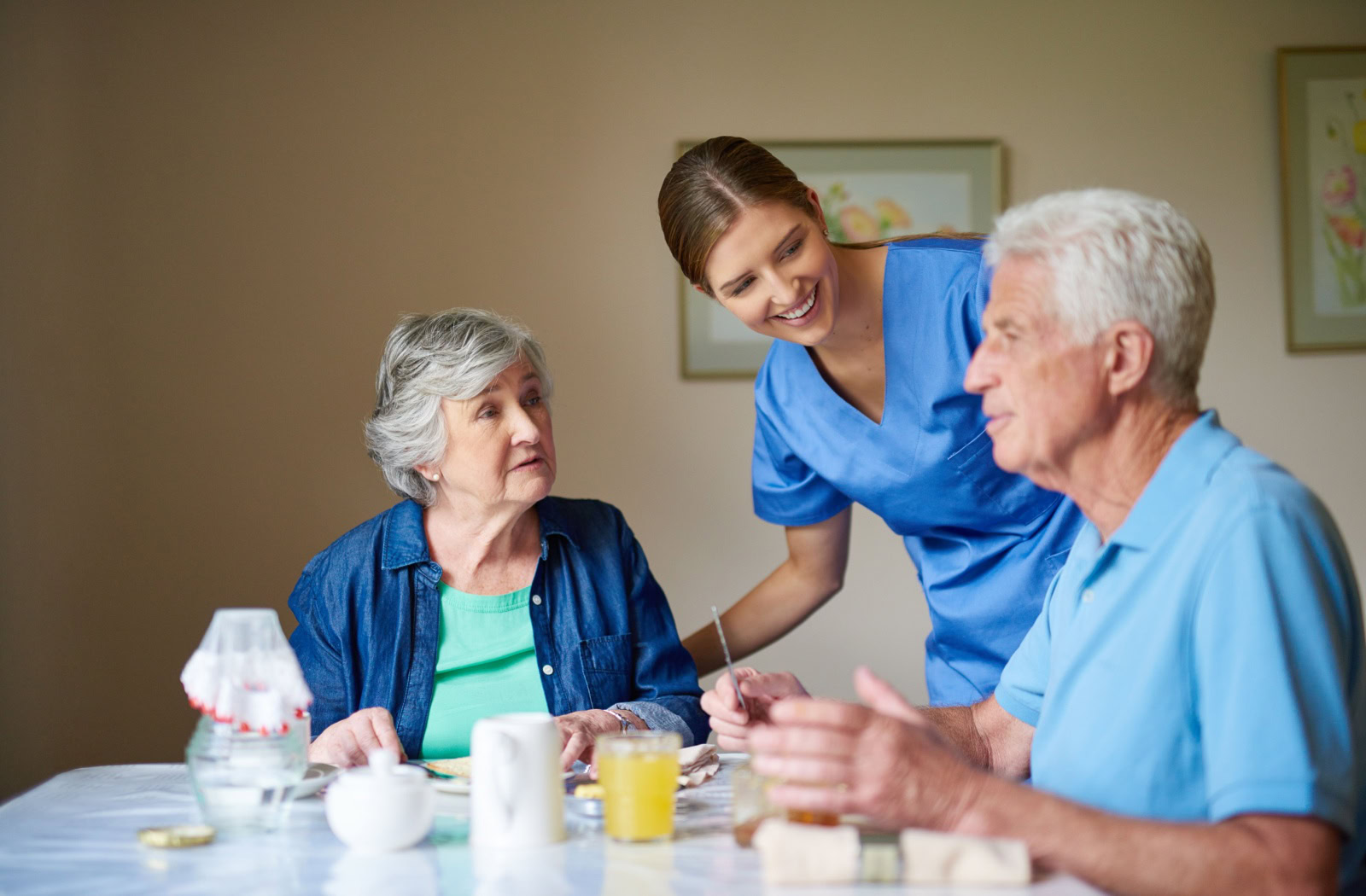 Seniors enjoy their meal while a staff member asks them if they would like anything more