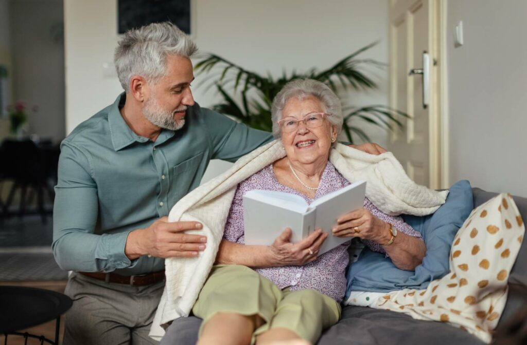 An adult child helps make their senior parent with dementia comfortable by offering a soft blanket to them.