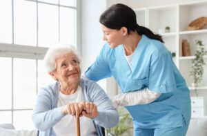 A caregiver in assisted living checking in on a smiling older adult with memory loss.