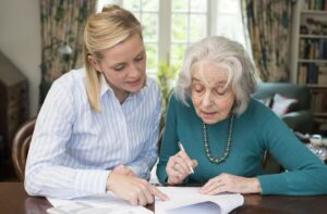 An adult child helping their parent with dementia through legal documents for guardianship in their home.