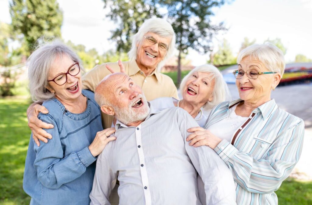group of older friends having fun and making silly poses for the camera while outdoors in the park.