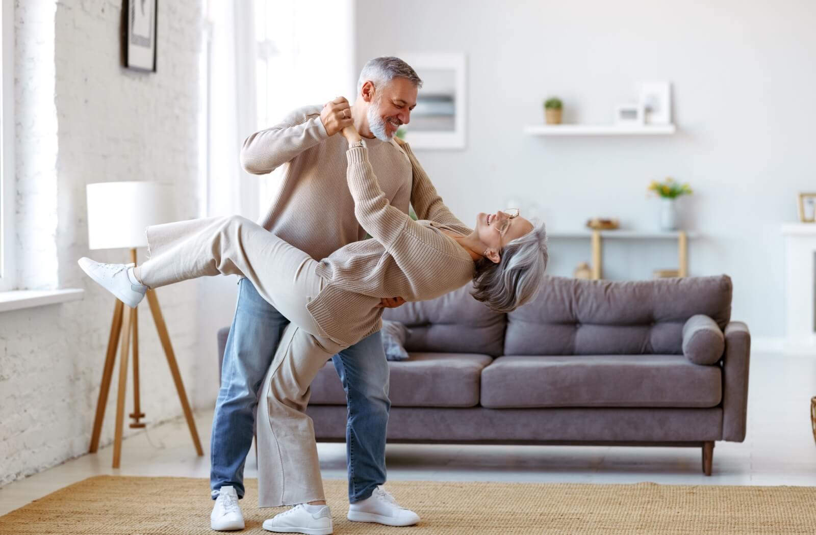 An older couple in independent living laughing and dancing in their new living room.