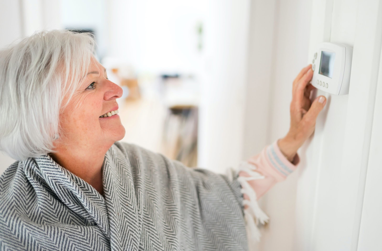 a senior woman ajdusts the temperature in her apartment