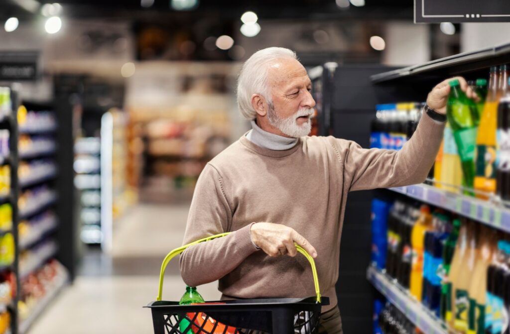 A senior at a clean, well-lit grocery store fills a basket full of pop, adding more sugary drinks to their diet